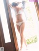 A woman in a white bikini standing in front of a door.