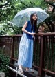 A woman in a blue dress holding an umbrella.