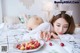 A woman laying on a bed with a plate of cherries.