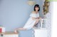 A woman in a white dress sitting on top of a dresser.