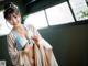 A woman in a blue and beige kimono posing for a picture.