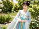 A woman in a blue and white hanbok standing in a garden.