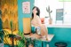 A woman sitting on top of a table next to a plant.