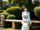 A woman in a blue and orange kimono sitting on a bench.