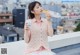 A woman sitting on a ledge eating a hot dog.