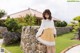 A woman leaning against a stone wall in a garden.