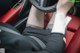 A woman sitting in a car with her feet on the steering wheel.