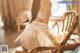 A woman in a white lingerie sitting on a chair.