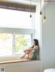 A woman sitting on a window sill looking out a window.