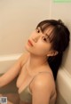 A woman sitting in a bathtub with her back to the camera.