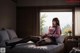 A woman sitting on a bed in front of a window.