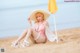 A woman in a pink bikini sitting on the beach.