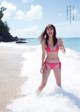 A woman in a pink bikini standing in the ocean.