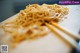 A wooden cutting board topped with noodles and chopsticks.